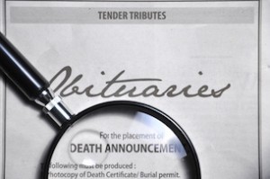 magnifying glass and obituaries advertisement on newspaper.